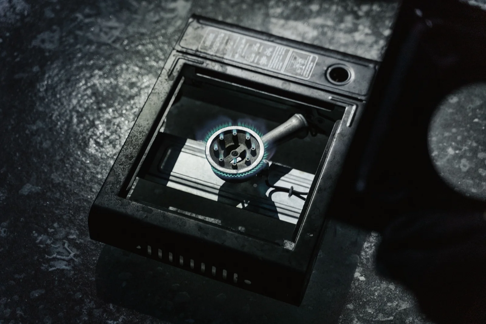 A lit portable gas stove seen from above, with a ring of blue flame